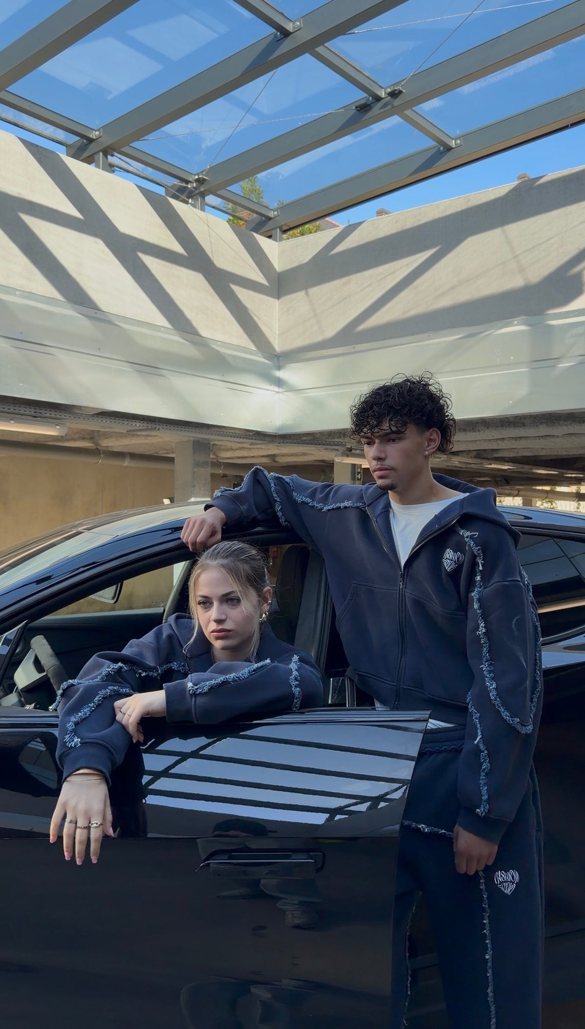 Samuel et Sara en ensemble Torn, posés sur la voiture